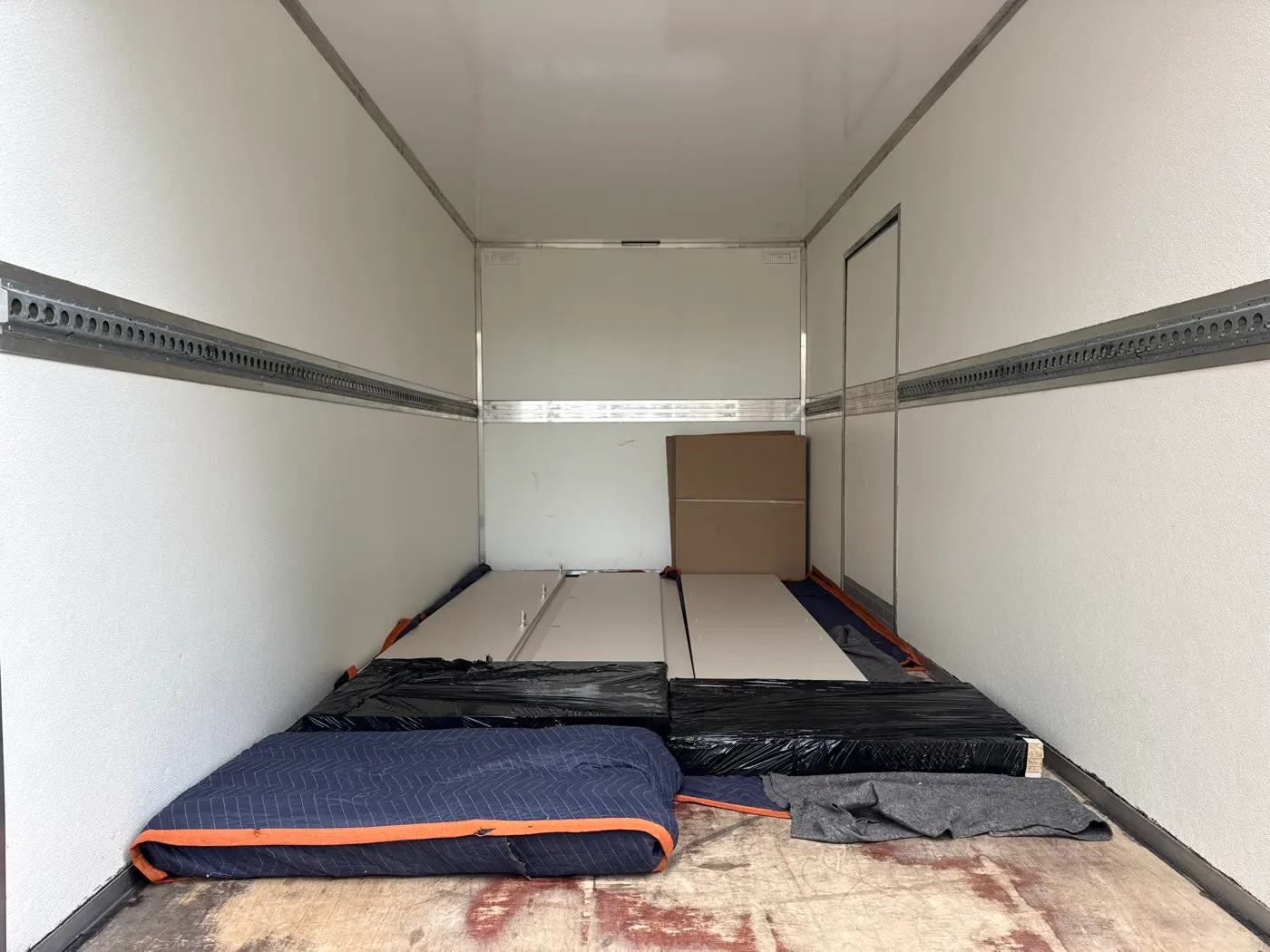 Puste wnętrze kufra busa z rozłożonymi kocami i zabezpieczonymi płytami przy ścianie
