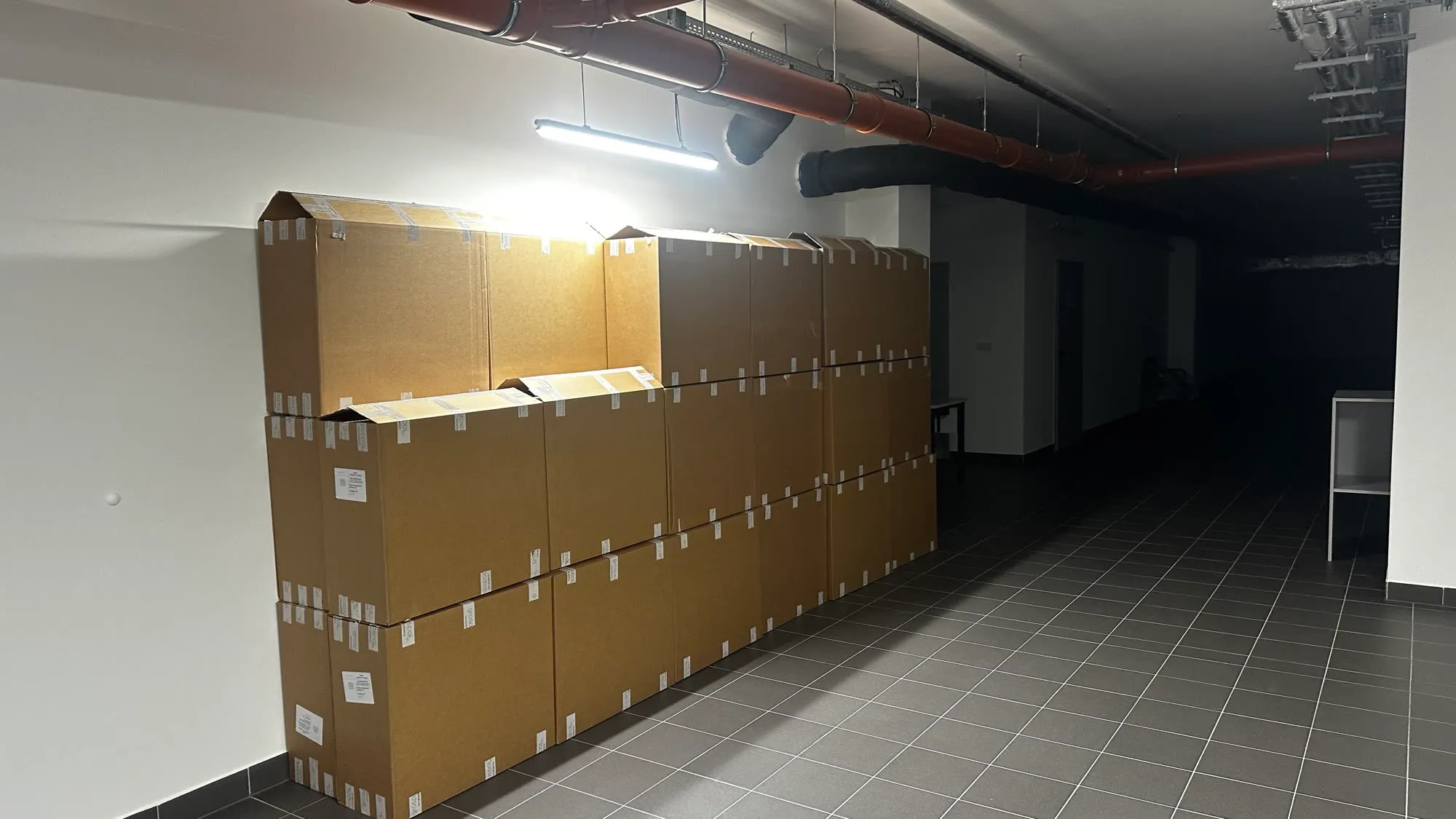 Rząd dużych kartonów ustawionych pod ścianą korytarza biurowego