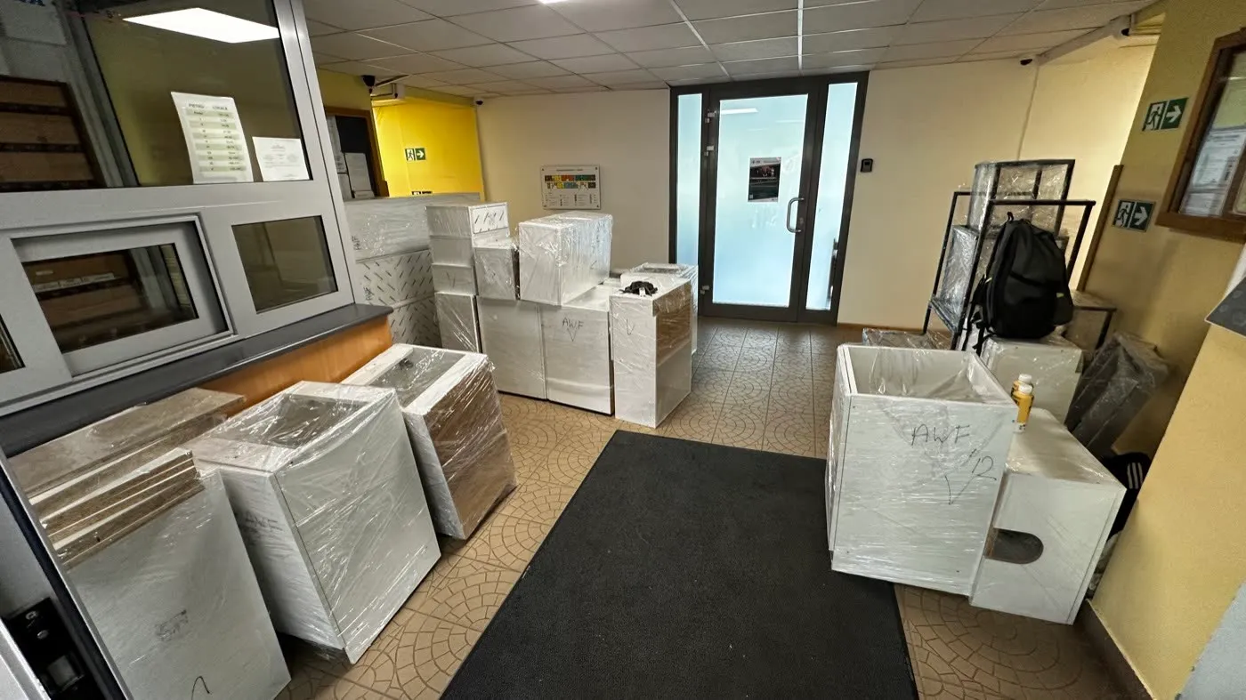 Meble biurowe owinięte folią, zestawione w recepcji budynku przed wyniesieniem