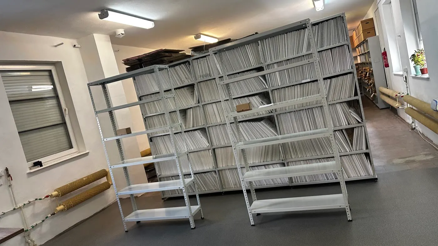 Metalowe regały z segregatorami archiwum i puste regały przygotowane do przeniesienia
