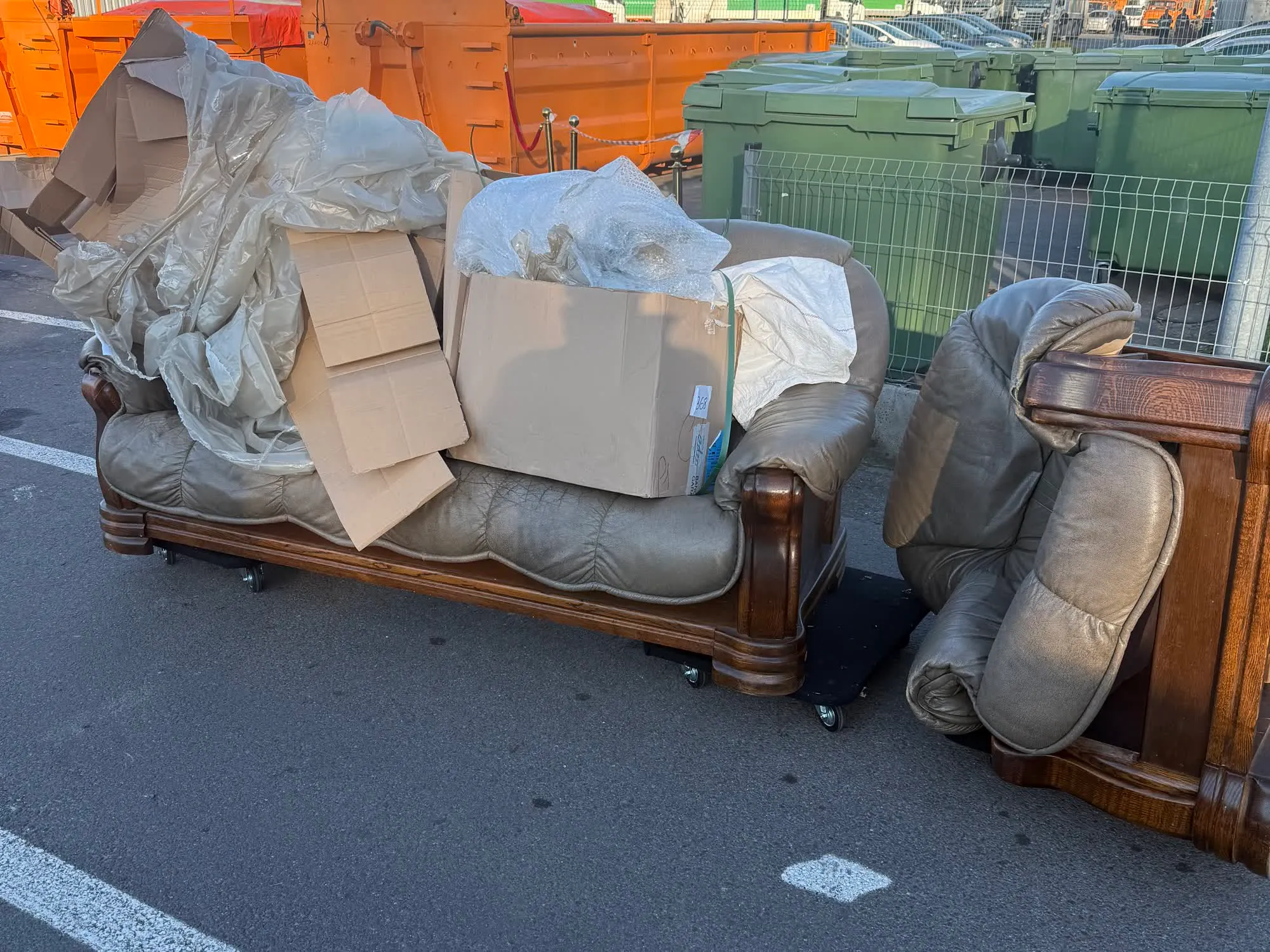 Kanapa i fotel na wózku transportowym przy kontenerach w punkcie odpadów