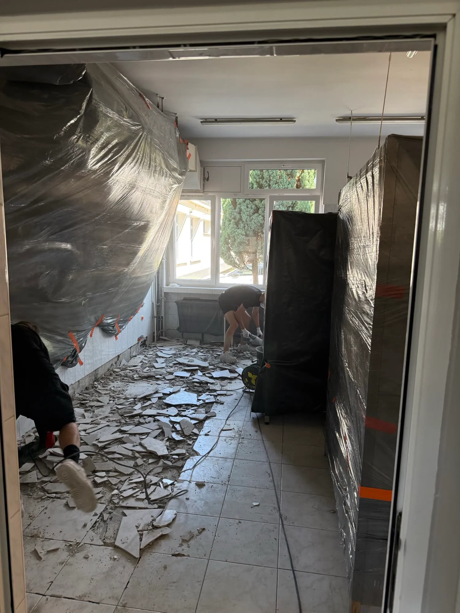 Pomieszczenie przygotowane do skuwania płytek, ściany i meble szczelnie osłonięte folią przyklejoną taśmą