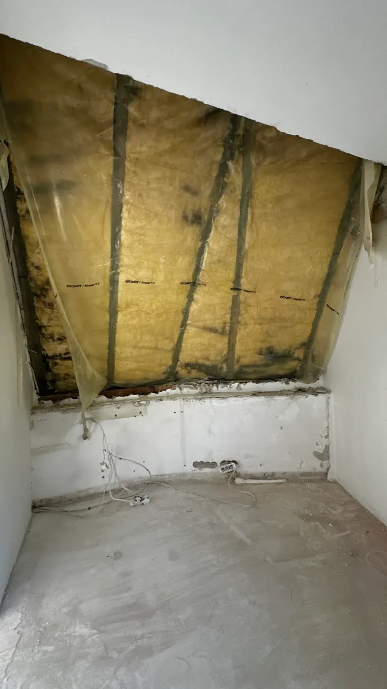 Skos poddasza z wełną mineralną pod folią paroizolacyjną, częściowo odsłonięta ściana